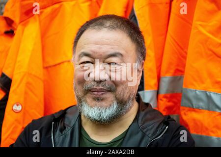 Berlino, Germania. 11th Feb, 2020. Ai Weiwei, artista cinese, è in piedi in studio di fronte alla sua opera 'sicurezza Giacche Zipped l'Altro Modo' nella 'parete della versione'. Le varie costruzioni di giacche di sicurezza, ganci e barre di ferro possono essere acquistate come parti individuali dallo sponsor Hornbach e assemblate da parti interessate stesse. Credit: Christoph Soeder/Dpa/Alamy Live News Foto Stock