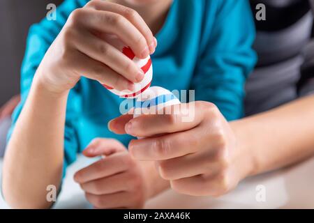 Mani di bambino con uova di Pasqua colorate che bussano. Pronto per la maschiatura delle uova in casa. Felice Pasqua ortodossa vacanza e rituale. Primo piano Foto Stock