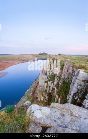 Lungo il percorso del Vallo di Adriano, lungo il percorso le scogliere di Highshield Crag si affaccia su Crag Lough nel Northumberland Foto Stock