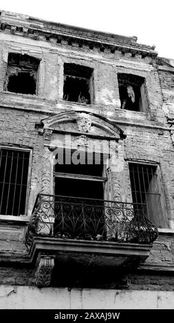 Facciata di una vecchia casa in mattoni o edificio decaduto e in rovina. Casa o edificio danneggiato o rovinato senza finestre. Fotografia in bianco e nero Foto Stock