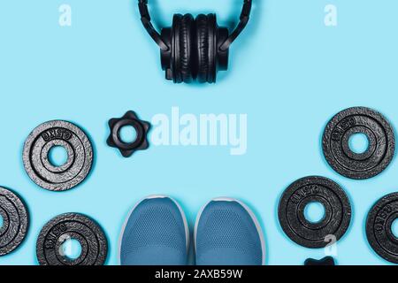 Foto sportiva. Manubri, sneakers e cuffie situate su un tappeto sportivo su sfondo verde menta. Disposizione piatta, vista dall'alto, spazio di copia. Foto Stock