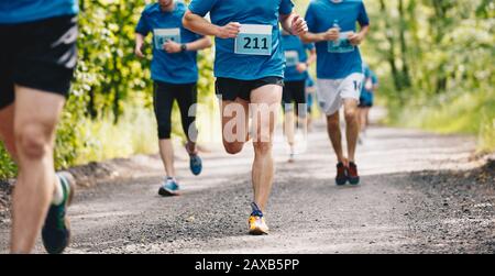 Gruppo di corridori che corrono velocemente attraverso la foresta durante il percorso della maratona Foto Stock