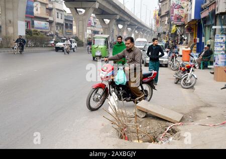 I pendolari attraversano nelle vicinanze un foro principale aperto che può causare qualsiasi grave incidente che dimostri la negligenza del reparto interessato, presso il Comitato Chowk di Rawalpindi martedì 11 febbraio 2020. Foto Stock