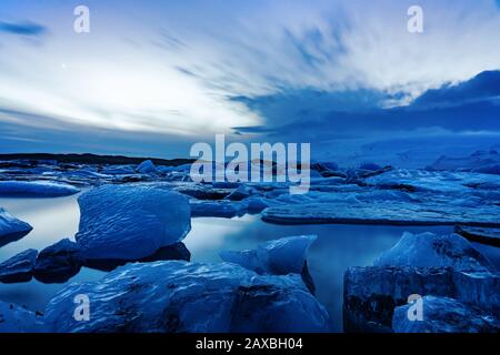 Ghiacciato ghiacciaio dell'islanda jokulsarlon negli iceberg serali che galleggiano sull'acqua fredda e tranquilla dopo il tramonto Foto Stock