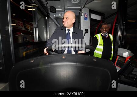 Il Cancelliere dello scacchiere Sajid Javid si trova nel posto di guida di un autobus mentre parla con un autista durante una visita al Birmingham Central Bus Garage. Foto Stock