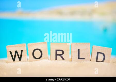 Spiaggia astratta - sabbia e mare con la parola - mondo di cubetti di legno. Concetto Di World Travel. Primo piano. Sfocato. Foto Stock