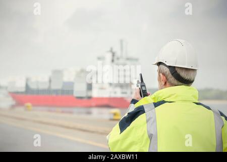 Dock manager con walkie-talkie che guarda container nave presso molo commerciale Foto Stock