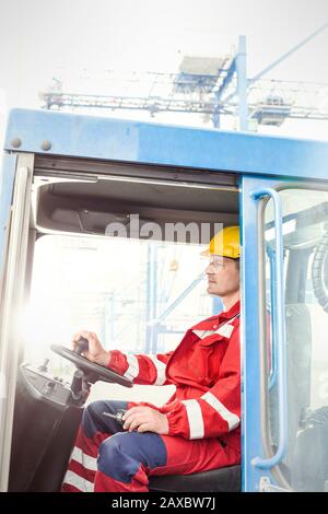 Operatore di banchina che guida carrello elevatore a forche presso il cantiere Foto Stock