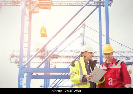 Operatore di ormeggio e manager con appunti che parlano sotto gru presso il cantiere navale Foto Stock