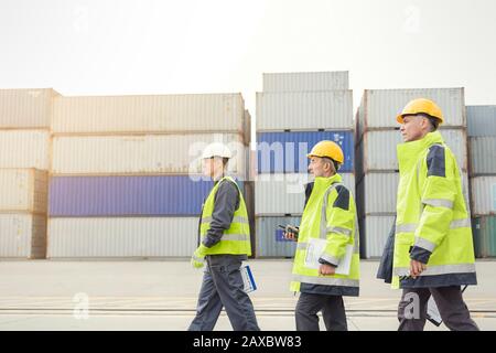 Ormeggia i lavoratori che camminano lungo i container del cantiere Foto Stock