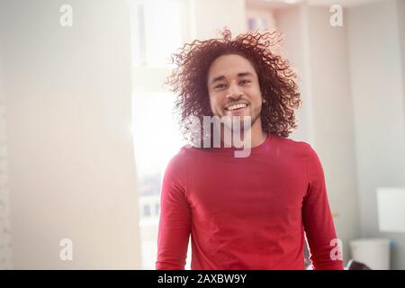 Ritratto sicuro, sorridente giovane uomo con capelli ricci Foto Stock