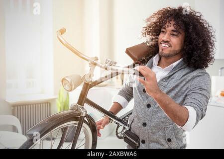Sorridente giovane uomo che porta bicicletta Foto Stock