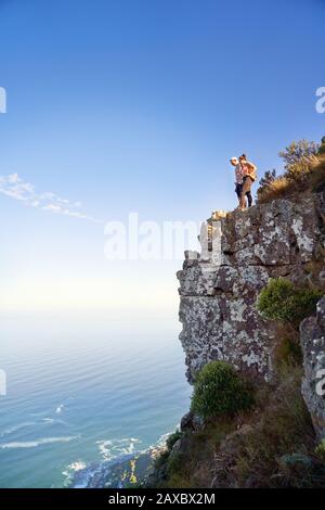 Coppia sulla scogliera sul soleggiato oceano di Città del Capo Sud Africa Foto Stock