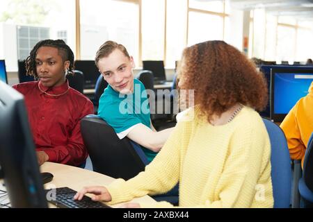 Studenti universitari che studiano insieme a computer in biblioteca Foto Stock