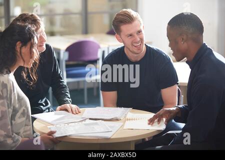 Giovani studenti universitari felici che parlano e studiano in biblioteca Foto Stock