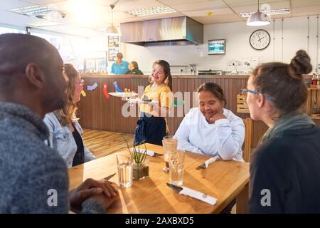 Giovane server femminile con Sindrome Di Down che serve dessert nel menu Foto Stock