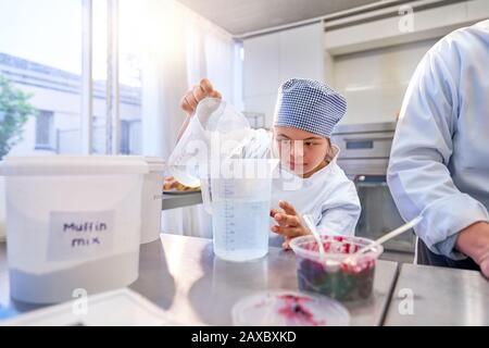 Giovane studentessa focalizzata con La Sindrome Di Down che cuoceva Foto Stock