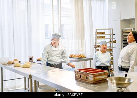 Chef felice e studenti con La Sindrome Di Down cottura in cucina Foto Stock