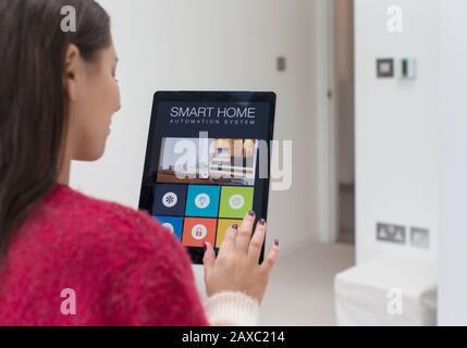 Donna che utilizza un sistema di automazione domestica intelligente con tablet digitale Foto Stock