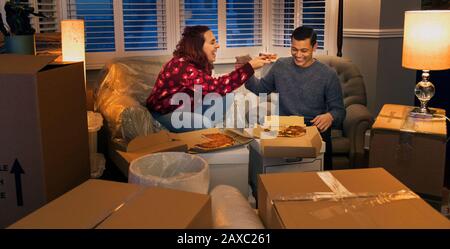 Coppia felice che prende una pausa dal muoversi, mangiare la pizza Foto Stock