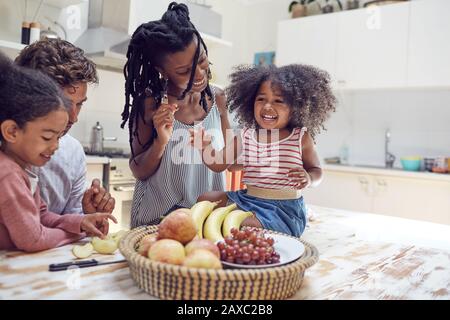 Giovane famiglia che mangia frutta in cucina Foto Stock