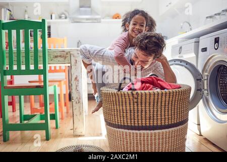 Giocoso padre e figlia che fanno lavanderia Foto Stock