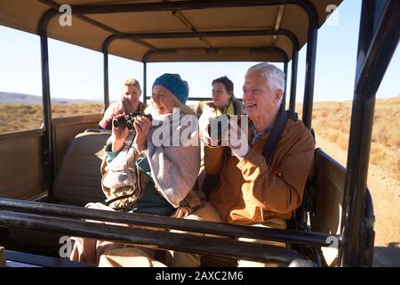 Happy Seniors con binocolo e macchina fotografica durante il safari in fuoristrada Foto Stock