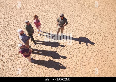 Guida turistica di Safari che parla con il gruppo su una terra piena di sole crepe Foto Stock