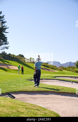 Buon uomo che gioca a golf sul soleggiato campo da golf Foto Stock