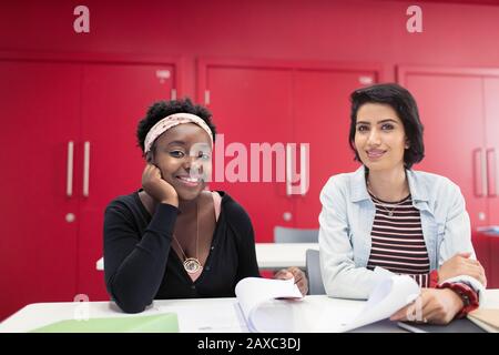 Ritratto sicuro, sorridente studentesse di comunità college con documenti in classe Foto Stock