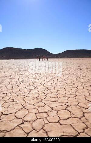 Safari gruppo tour a piedi lungo la soleggiata terra cracked Sud Africa Foto Stock