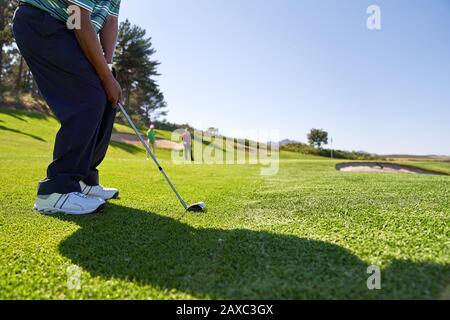 Golfista maschile che prende un colpo sul campo da golf soleggiato Foto Stock