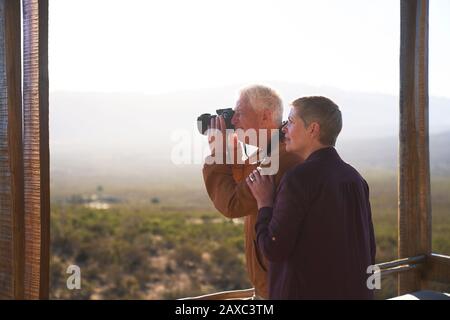 Coppia senior con macchina fotografica sul soleggiato balcone safari Foto Stock