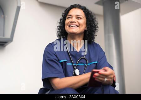 Ritratto sorridente, medico felice femminile utilizzando smartphone Foto Stock