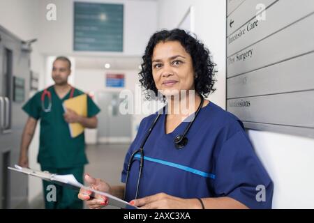 Ritratto sicuro medico femminile con carta medica, facendo giri nel corridoio dell'ospedale Foto Stock