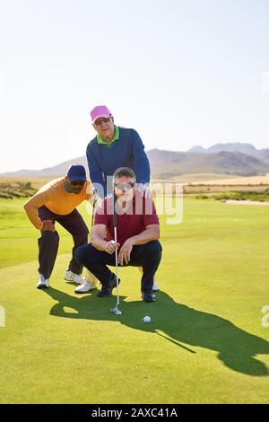 Golfers maschio che progettano il putt sparato sul campo da golf soleggiato che mette il verde Foto Stock