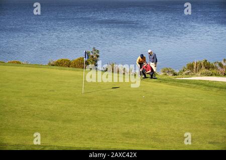 Golfers maschio che progettano il putt sparato al campo da golf soleggiato del lago Foto Stock