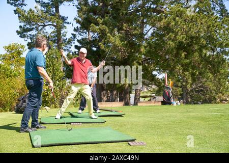Felice golfer maschio anziano che gheering al campo da golf soleggiato che guida il campo Foto Stock