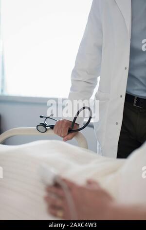 Medico con stetoscopio che fa giri in stanza dell'ospedale Foto Stock