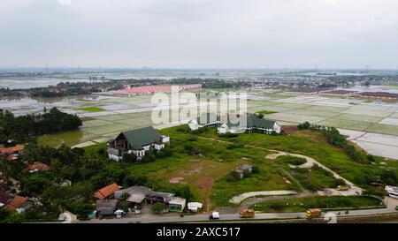 Volo Aereo. Le case di campagna e i campi circondati da alberi verdi e risaie Foto Stock