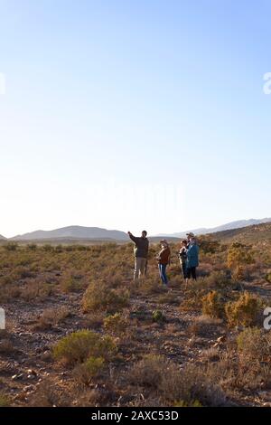 Guida turistica Safari che parla con il gruppo in un'assolata prateria remota Foto Stock