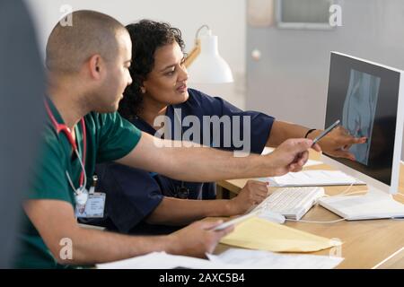 Infermieri che esaminano i raggi X digitali presso il computer presso l'ufficio dei medici Foto Stock