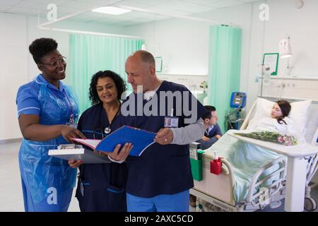 Medici e infermieri con cartelle mediche, consulenza in reparto ospedaliero Foto Stock