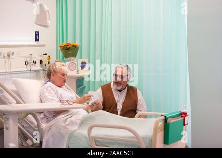 Uomo anziano che visita la moglie che riposa nella stanza dell'ospedale Foto Stock