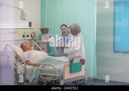 I medici facendo turni, parlando con il paziente nella stanza di ospedale Foto Stock