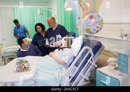 Medici che fanno i giri, parlando con la coppia nel reparto dell'ospedale Foto Stock