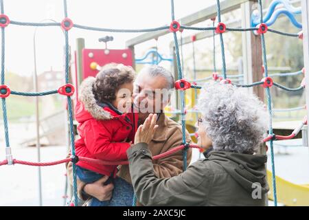 Nonni che giocano con il nipote nel parco giochi Foto Stock