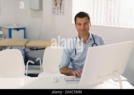 Ritratto medico sicuro maschio che lavora al computer in ufficio medici Foto Stock