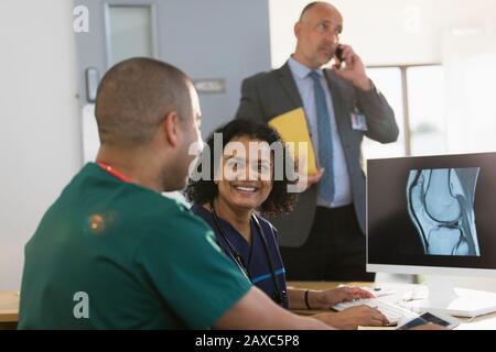 Infermieri sorridenti che discutono di raggi X digitali al computer in clinica Foto Stock