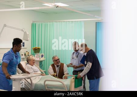 Medici che fanno giri, parlando con il paziente anziano nella stanza dell'ospedale Foto Stock